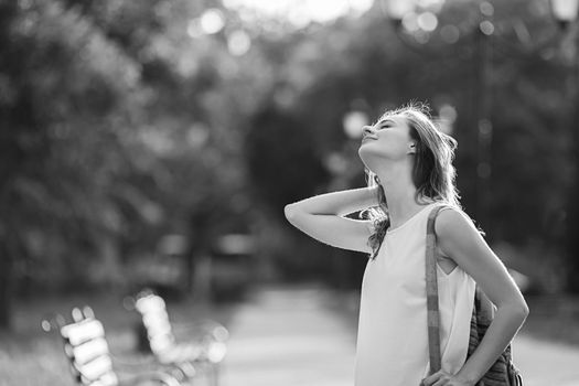 Portrait of lovely urban girl with backpack in the street. Portrait of a happy smiling woman. Fashionable blonde girl having fun outdoors in the city. Black and white photo