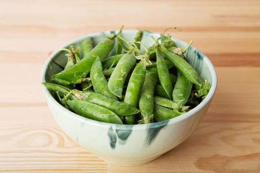 green peas in pods freshly picked on wood. Some green peas. Fresh green peas. green pods with peas as background. Green peas into a bowl