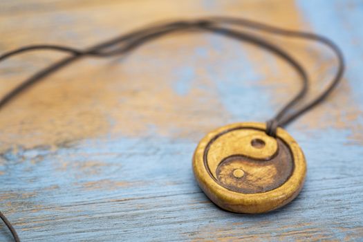 essential oil diffuser ceramic pendant with yin and yang symbol on grunge wood - selective focus