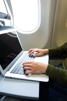 Woman using notebook computer inside airplane