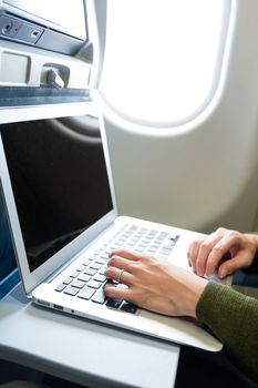 Woman working on notebook computer in airplane