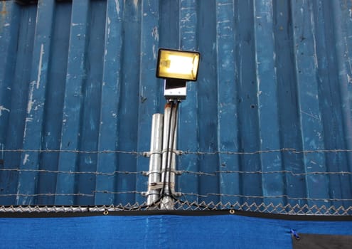 Surveillance Search Light on Blue Metal Background with Barbwire