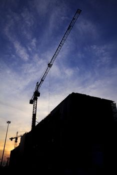 Silhouette of construction workers on scaffold working under a hot sun