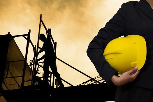 engineer holding Yellow helmet for workers security on background of building construction