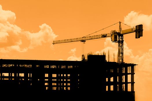 Silhouette of construction workers on scaffold working under a hot sun