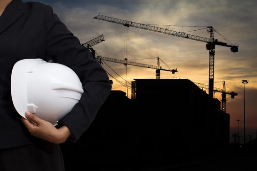 engineer holding white helmet for workers security on background of building construction