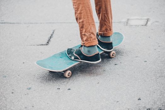 Young skateboarder in gumshoes standing on skate