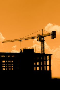 Silhouette of construction workers on scaffold working under a hot sun