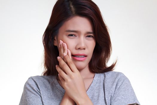 Teen woman pressing her bruised cheek with a painful expression as if she's having a terrible tooth ache.