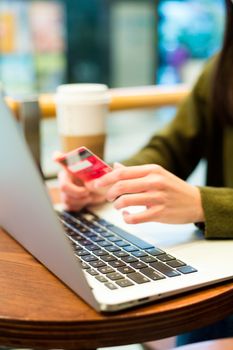 Hands holding credit card and using laptop