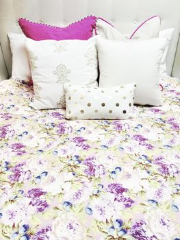 White and purple bed linen with floral design. Close-up of a bed.