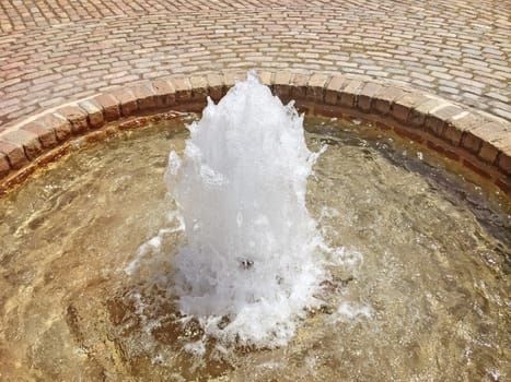 Little simple fountain on a paved city square.