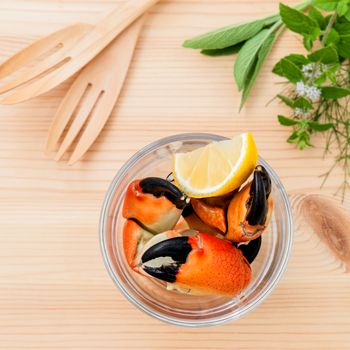 Fresh steamed red crabs leg in glass bowl . Red crabs leg with ingredients. Steamed red crabs leg with herbs Fennel ,parsley,rosemary,lemon and mint with fork on wooded background.