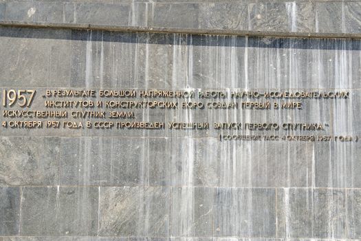 Moscow, Russia - August 10, 2015: The inscription with the TASS report on the withdrawal of artificial earth satellite at the foot of the monument "Conquerors of Space" in Moscow