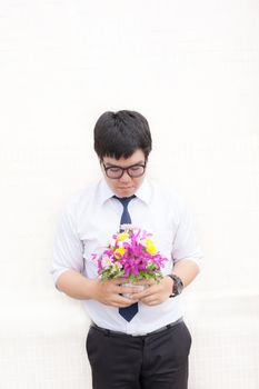 Waiting for his girlfriend. Close up of handsome young man holding bouquet of flowers stand in front of the concrete wall .
