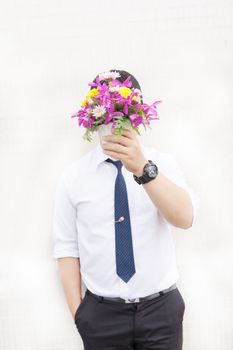 Waiting for his girlfriend. Close up of handsome young man holding bouquet of flowers stand in front of the concrete wall .