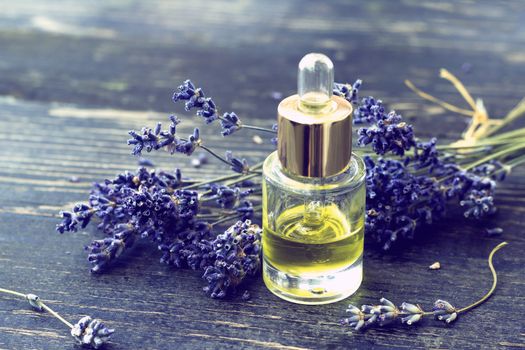 Bottle of lavender oil and lavender flowers on wooden background -  - vintage stylized photo