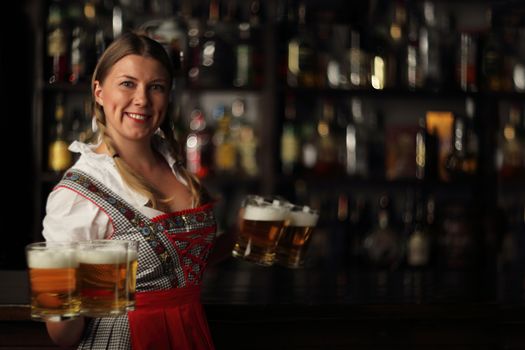 Pretty oktoberfest blonde woman holding beer bugs in bar