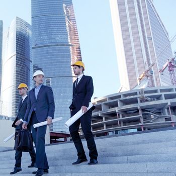 Architects with blueprint at skyscrapers background