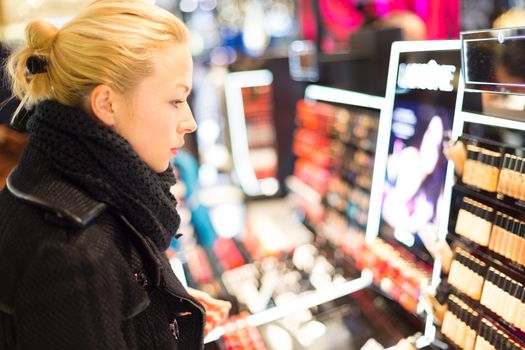 Beautiful blond lady testing  and buying cosmetics in a beauty store.