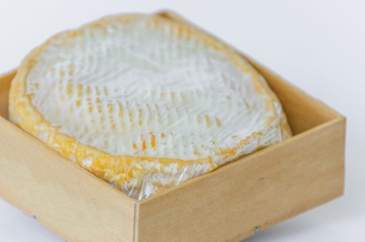 Round white Camembert in a small wooden box.