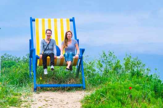 Two young women in a giant deckchair.