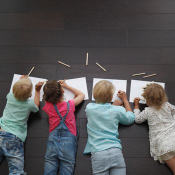 Group of cute children drawing with colorful pencils on floor