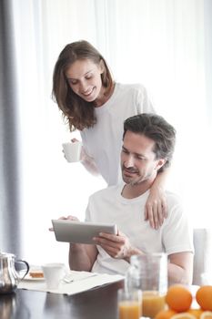 Couple having breakfast at home and using tablet