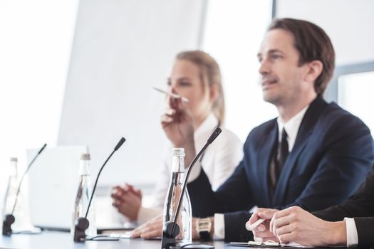 Business people speaking at presentation in microphones in office