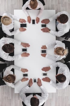 Business people sitting around the table with cell phones