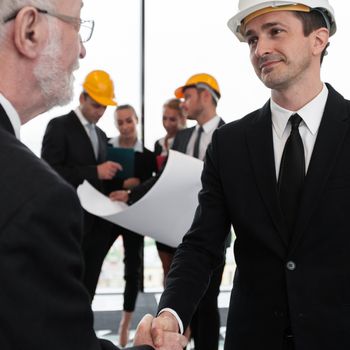 Handshake of architect and investor, business team with blueprint on background