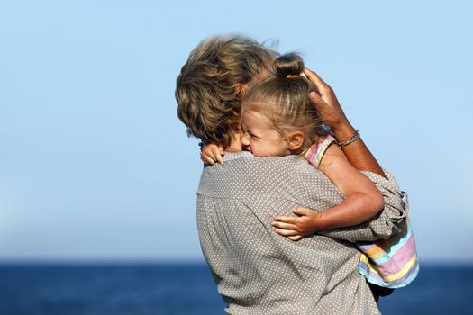 Grandmother with a little granddaughter on the beach