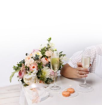 Two glasses with champagne, boutonniere with roses and cookies