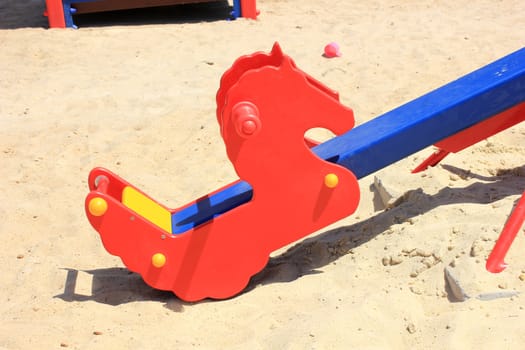 Seat on a children's swing in the form of red horses