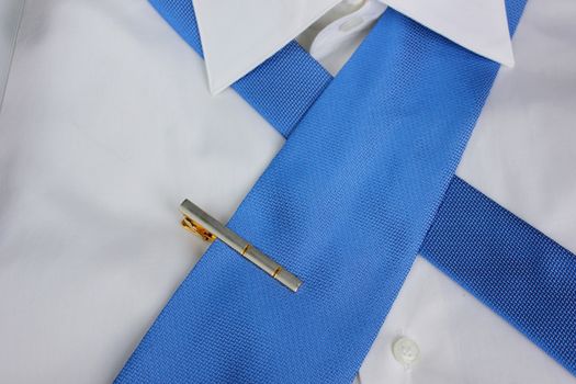 Gilded pin for a tie on a white shirt 