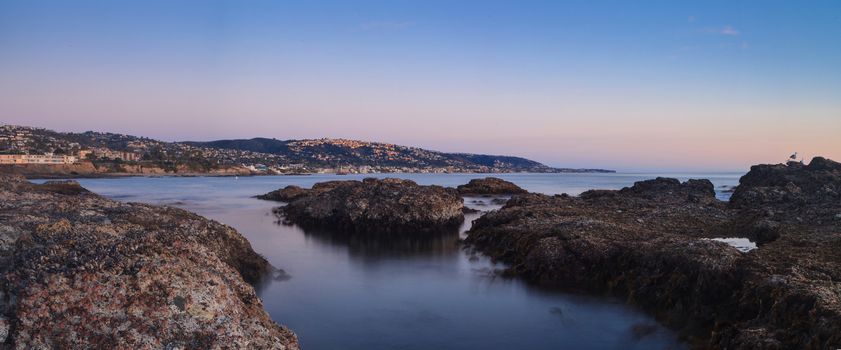 Long exposure of sunset over rocks, giving a mist like effect over ocean in Laguna Beach, California, United States