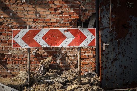 Flecked with shrapnel brick wall, door and road sign from parking of Donetsk airport after heavy and continuous shelling.