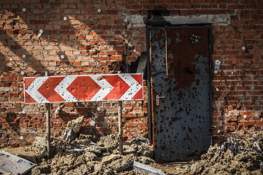 Flecked with shrapnel brick wall, door and road sign from parking of Donetsk airport after heavy and continuous shelling.