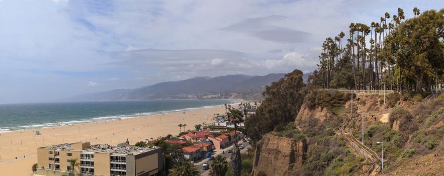 Along the Santa Monica coastline with a blue sky over the white sand of the beach in Southern California, United States.