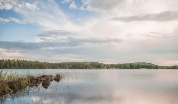 Lake with Rocks and Forest with a cloudy sky.