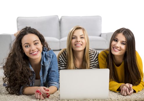 Happy teen girls studying at home with a laptop