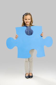 Beautiful little girl holding a big blue Puzzle