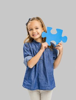 Beautiful little girl holding a blue Puzzle