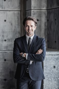 Portrait of smiling businessman in suit over concrete wall background