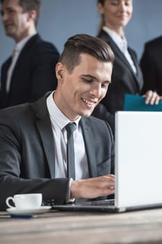Business man using laptop in office, business team on background
