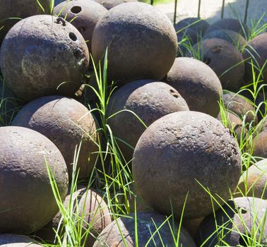 pile of old stone cannon balls overgrown with green grass