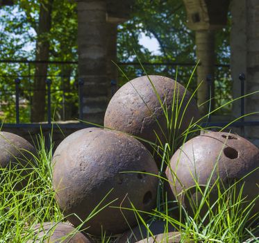 pile of old stone cannon balls overgrown with green grass