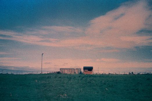 Color film image of sheds in a field in Laurencekirk