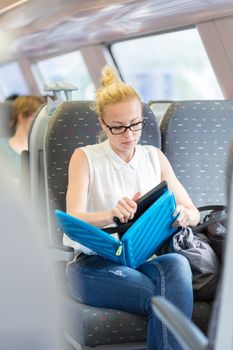 Businesswoman sitting and traveling by train working on laptop. Business travel concept.