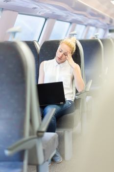 Businesswoman naping sitted while traveling by train and working on laptop. Tiresome business travel.